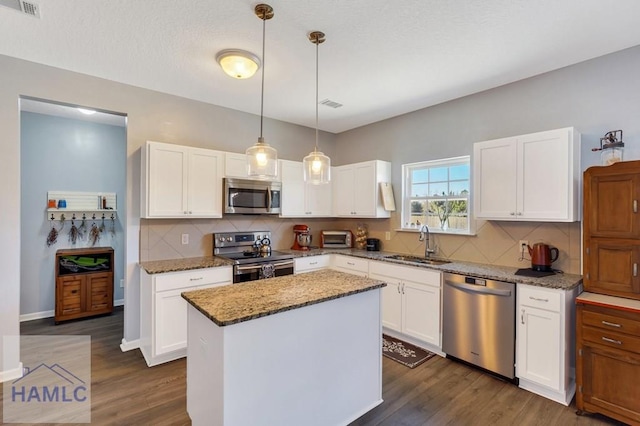 kitchen featuring visible vents, dark stone counters, white cabinetry, a sink, and appliances with stainless steel finishes