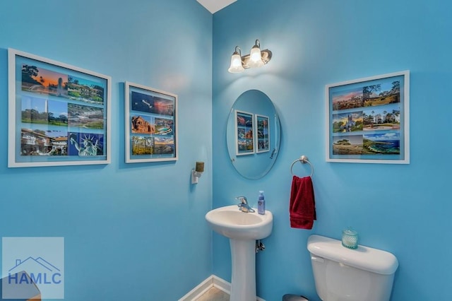 bathroom with a sink, baseboards, and toilet
