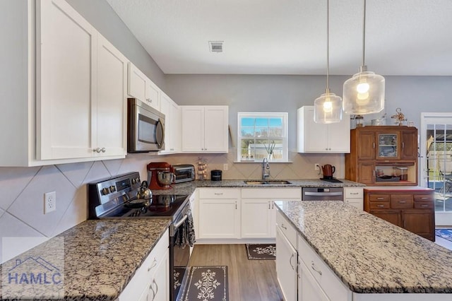 kitchen featuring a sink, stainless steel appliances, light wood-type flooring, tasteful backsplash, and visible vents