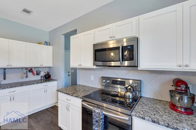 kitchen featuring white cabinets, stainless steel appliances, visible vents, and tasteful backsplash