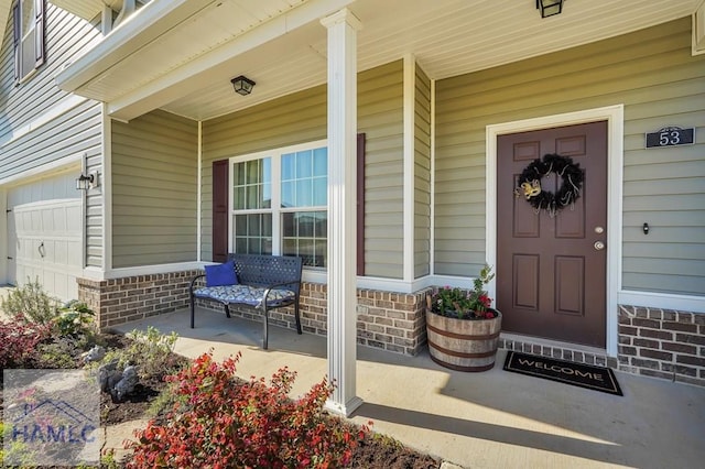 entrance to property with a porch and brick siding