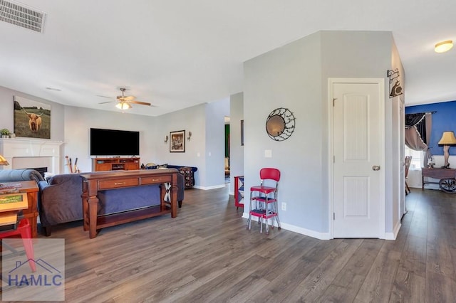 living room with ceiling fan, a fireplace, baseboards, wood finished floors, and visible vents