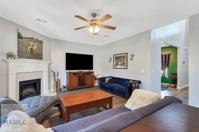living area featuring a ceiling fan, baseboards, visible vents, and wood finished floors