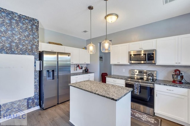 kitchen featuring white cabinets, wood finished floors, a kitchen island, and stainless steel appliances