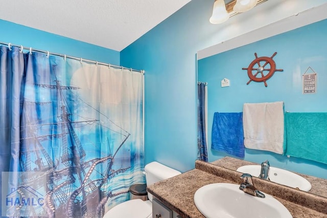 full bathroom featuring vanity, a shower with curtain, toilet, and a textured ceiling