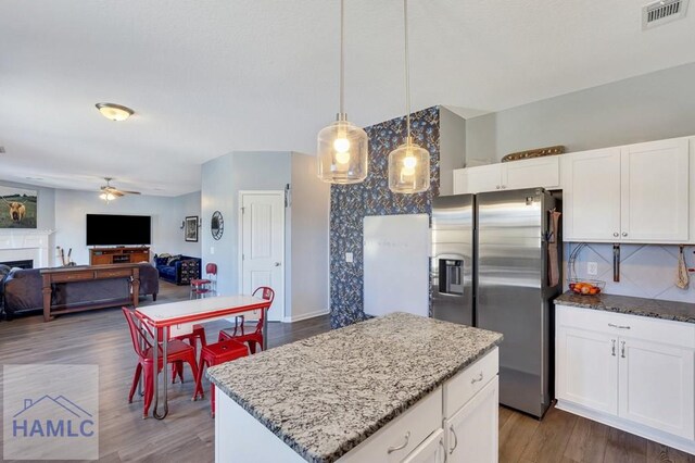 kitchen featuring visible vents, light stone countertops, stainless steel refrigerator with ice dispenser, a ceiling fan, and dark wood finished floors