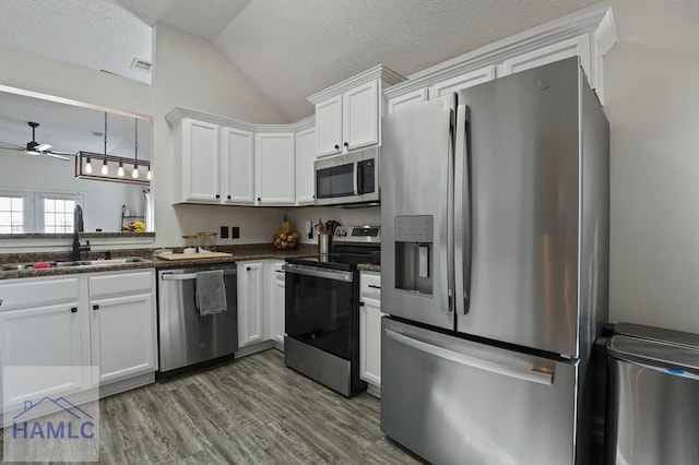 99 Scarlett Ln, Richmond Hill, GA 31324 - kitchen with appliances with stainless steel finishes, a ceiling fan, vaulted ceiling, white cabinets, and wood finished floors