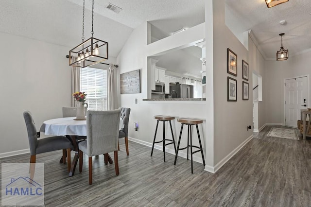 99 Scarlett Ln, Richmond Hill, GA 31324 - dining area featuring a textured ceiling, dark wood-style flooring, vaulted ceiling, and a chandelier