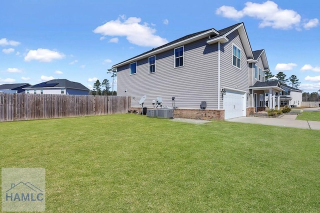 view of side of home featuring an attached garage, brick siding, fence, a yard, and driveway