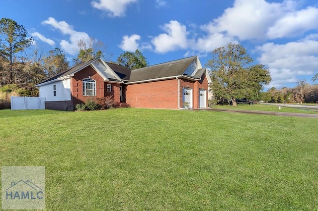 view of front facade with driveway, brick siding, an attached garage, and a front yard