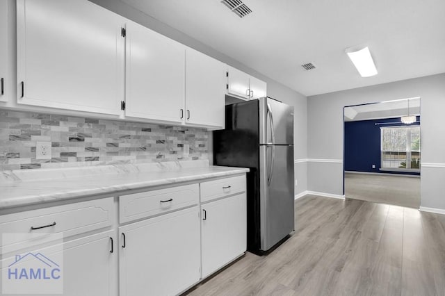 kitchen featuring stainless steel refrigerator, white cabinetry, light hardwood / wood-style flooring, and tasteful backsplash