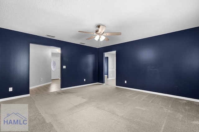 carpeted empty room featuring ceiling fan and a textured ceiling