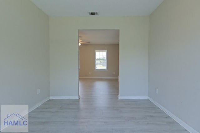 spare room featuring baseboards, visible vents, a ceiling fan, and light wood-style flooring
