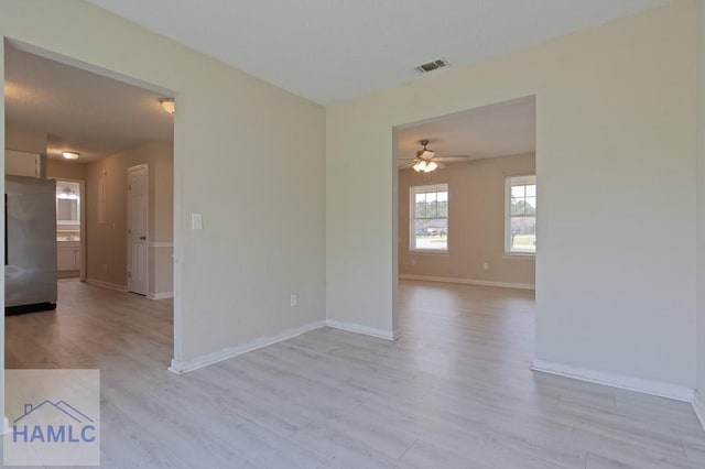 spare room featuring visible vents, ceiling fan, light wood finished floors, and baseboards