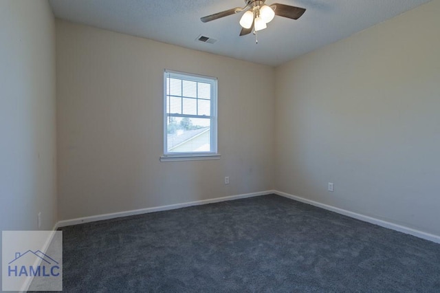 spare room featuring dark carpet, ceiling fan, visible vents, and baseboards