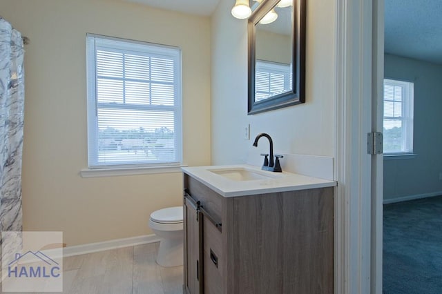 full bathroom with toilet, vanity, and baseboards