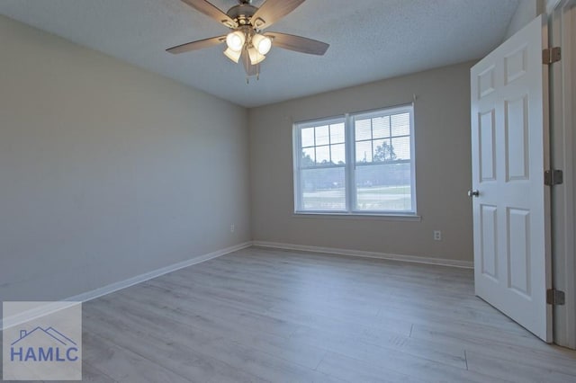 empty room with baseboards, a ceiling fan, a textured ceiling, and light wood finished floors