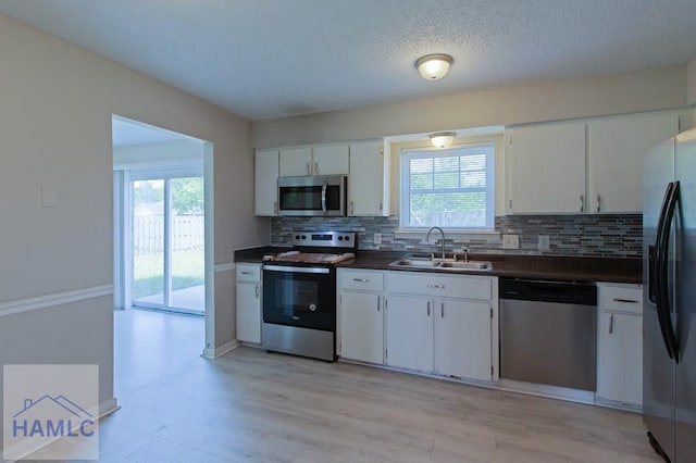 kitchen featuring dark countertops, a sink, a wealth of natural light, and stainless steel appliances