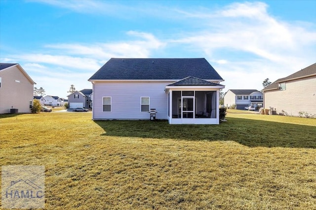 back of house with a residential view, a shingled roof, a sunroom, and a yard