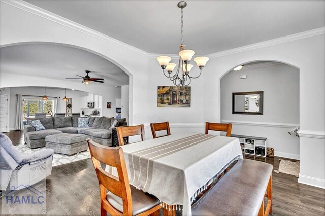 dining area with crown molding, baseboards, wood finished floors, arched walkways, and ceiling fan with notable chandelier