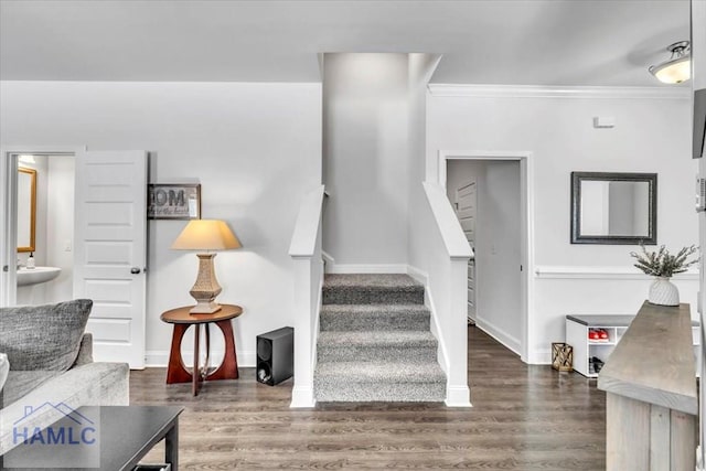 staircase featuring baseboards, ornamental molding, and wood finished floors