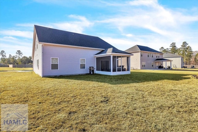 back of property with a lawn, a sunroom, and a shingled roof