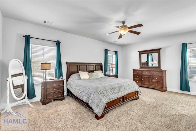 bedroom with light carpet, multiple windows, visible vents, and baseboards