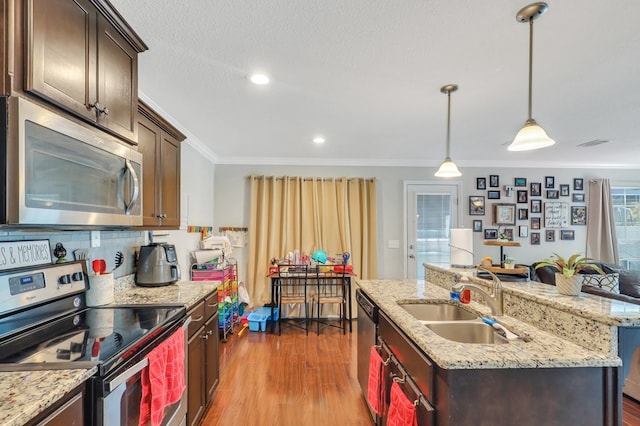 kitchen with appliances with stainless steel finishes, an island with sink, hardwood / wood-style flooring, and sink