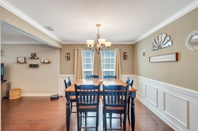 dining area featuring dark hardwood / wood-style flooring, ornamental molding, a textured ceiling, and an inviting chandelier