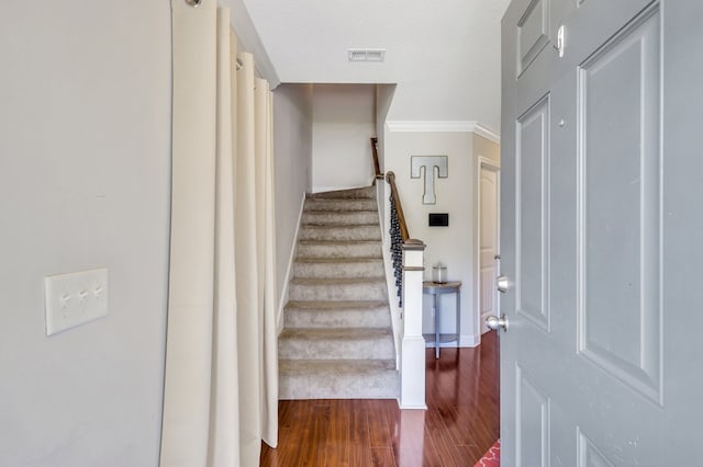 staircase featuring crown molding, a textured ceiling, and hardwood / wood-style flooring