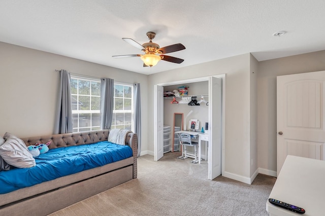 bedroom with ceiling fan, a closet, light colored carpet, and a textured ceiling