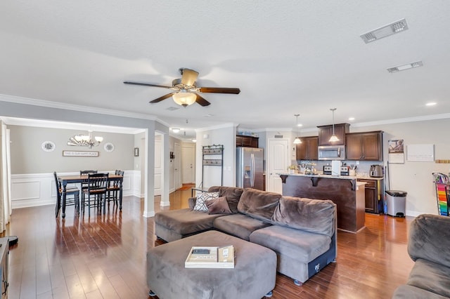 living room featuring a textured ceiling, ceiling fan with notable chandelier, crown molding, and dark wood-type flooring