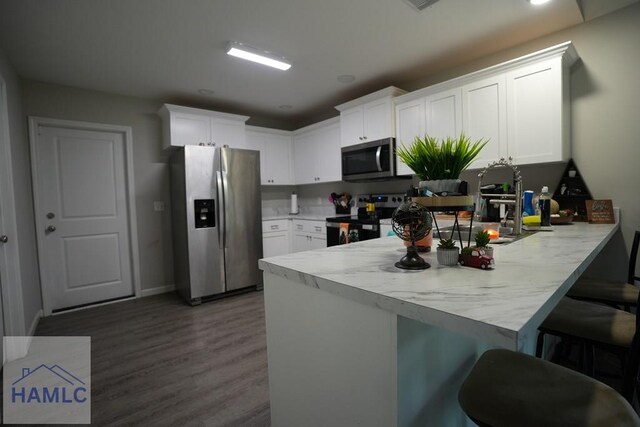 613 Macon St, Ludowici, GA 31316 - kitchen featuring appliances with stainless steel finishes, a peninsula, wood finished floors, light countertops, and white cabinetry