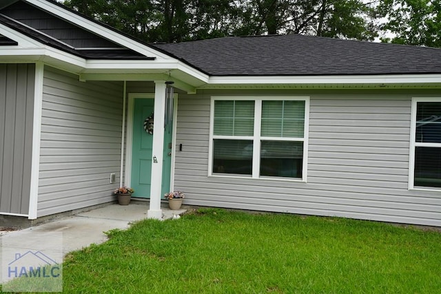 613 Macon St, Ludowici, GA 31316 - view of exterior entry featuring a lawn and a shingled roof