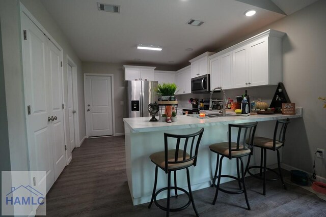 613 Macon St, Ludowici, GA 31316 - kitchen with appliances with stainless steel finishes, a peninsula, light countertops, white cabinets, and recessed lighting