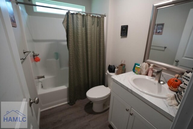 613 Macon St, Ludowici, GA 31316 - bathroom featuring wood finished floors, toilet, vanity, and shower / tub combo with curtain