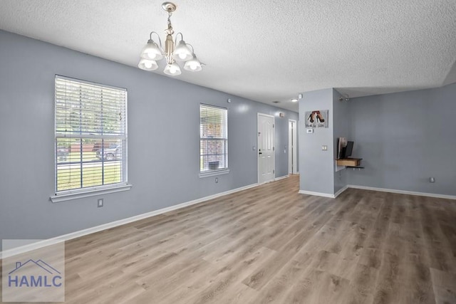 926 Poppleton Dr, Hinesville, GA 31313 - unfurnished living room with a textured ceiling, a chandelier, plenty of natural light, wood finished floors, and baseboards