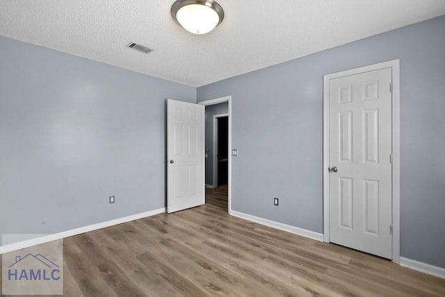 926 Poppleton Dr, Hinesville, GA 31313 - unfurnished bedroom with baseboards, wood finished floors, and a textured ceiling
