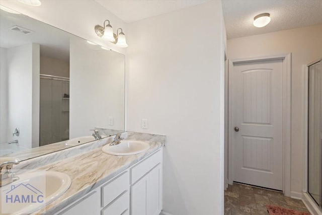 bathroom with vanity, a shower with door, and a textured ceiling