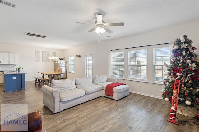 living room featuring sink, dark hardwood / wood-style floors, and ceiling fan with notable chandelier