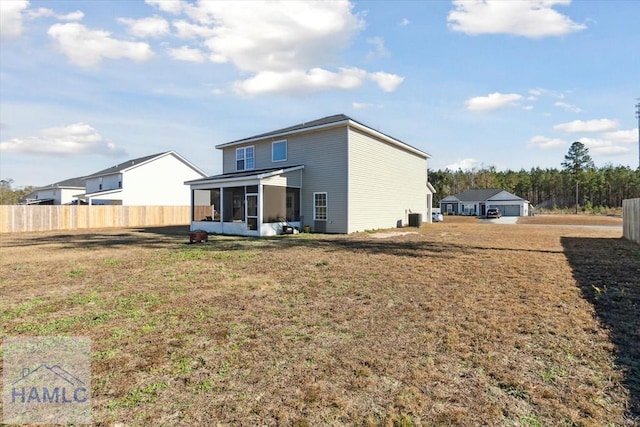 rear view of house featuring a sunroom and a yard