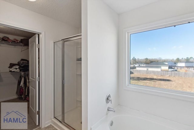 bathroom featuring shower with separate bathtub and a textured ceiling