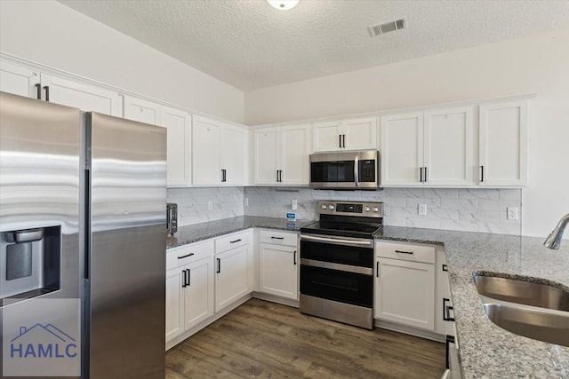 kitchen with light stone counters, sink, white cabinets, and stainless steel appliances