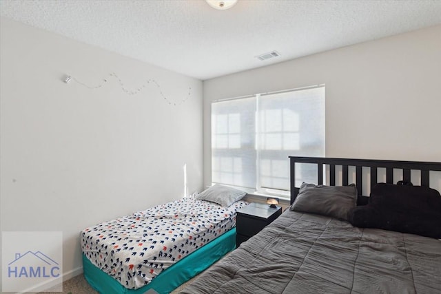 bedroom with dark carpet and a textured ceiling