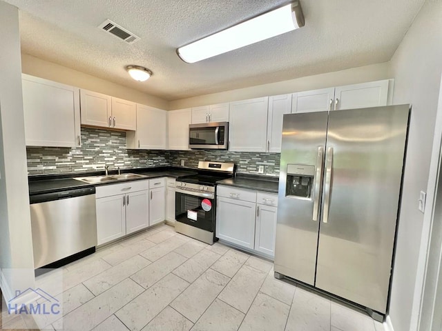 kitchen featuring tasteful backsplash, sink, white cabinets, and stainless steel appliances