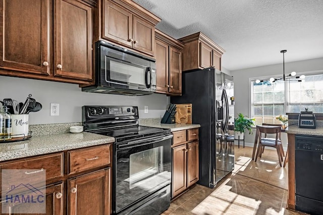 kitchen featuring an inviting chandelier, black appliances, dark tile patterned flooring, hanging light fixtures, and a textured ceiling