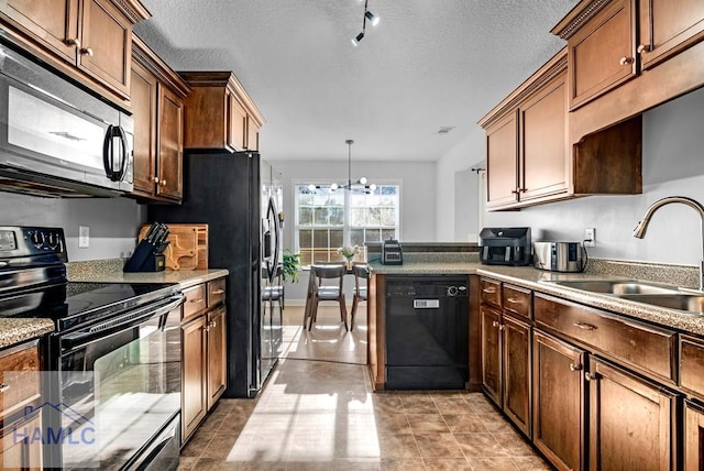 kitchen featuring black appliances, sink, light tile patterned floors, decorative light fixtures, and a chandelier