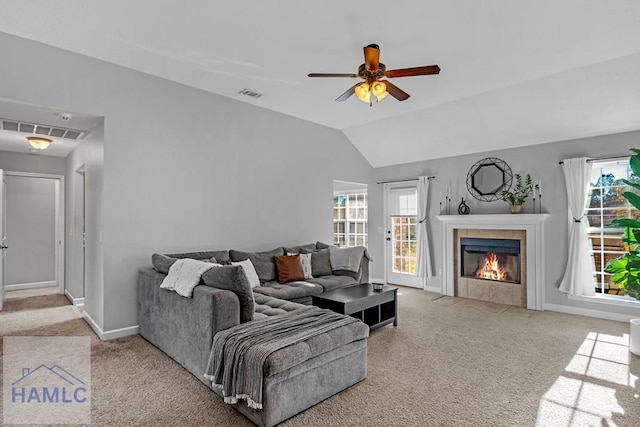 living room featuring ceiling fan, a fireplace, light carpet, and vaulted ceiling