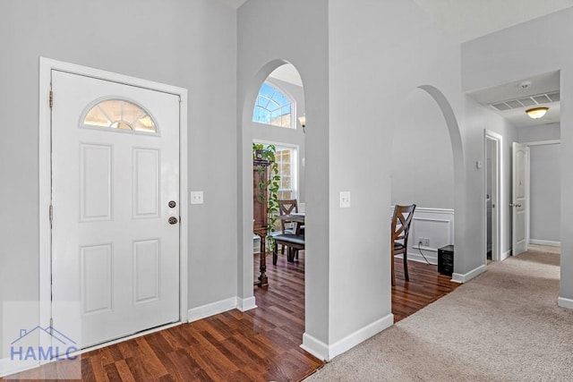 carpeted foyer entrance featuring a towering ceiling