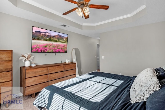 carpeted bedroom with a raised ceiling, ceiling fan, and crown molding